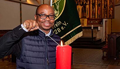 Ein Mann in einer Kirche zündet eine Kerze an.